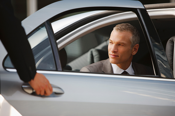 Chauffeurs opening car door for man from the back seat