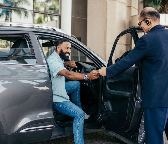 Chauffeurs opening car door for man from the front seat